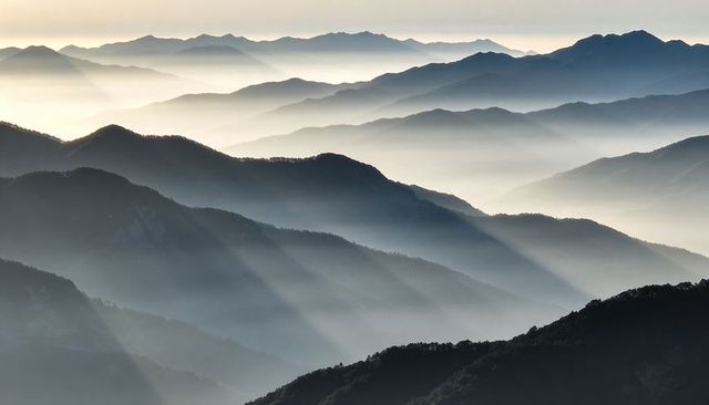 Sunrise light revealing layered mountain ridges and misty valleys creating serene panorama