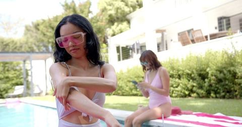 Biracial Woman Applying Sunscreen by Poolside on Sunny Day