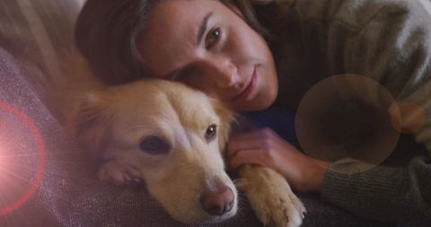 Woman Cradling Dog on Sofa with Warm Natural Light