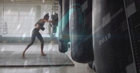 Woman boxer training with heavy bag in boxing gym