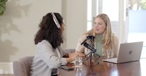 Diverse female podcasters collaborating in modern studio