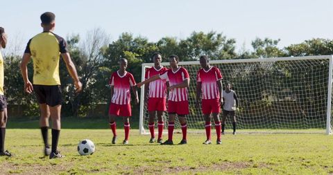 Diverse Soccer Team Practicing Free Kick on Field Against Grass Setup