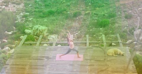 Woman practicing yoga on rustic deck in nature with loyal dog