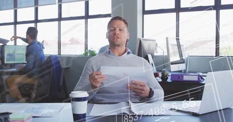Businessman Presenting Financial Report in Modern Open Office with Laptop and Coffee