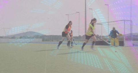 Female field hockey player sprinting on turf while goalkeeper defending