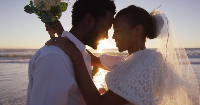 Newlywed couple enjoying their romantic beach wedding at sunset. This image can be used for wedding invitations, bridal magazines, romance articles, or any content celebrating love and marriage.
