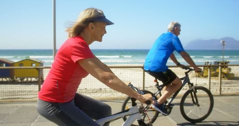 Senior Couple Enjoying Bicycle Ride on Sunny Beach Promenade