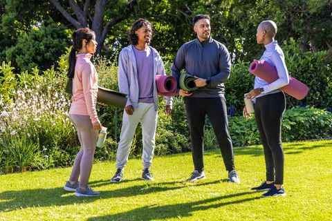 African american friends meeting for outdoor yoga session in sunny garden park