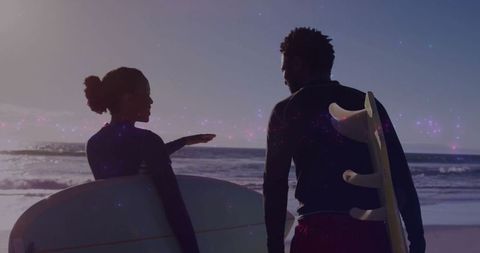 Surfers Walking with Boards at Sunset on Scenic Beach