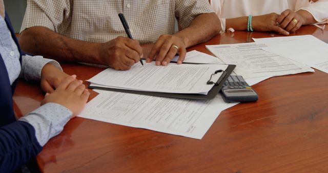 Business Meeting with Paperwork and Calculations at Wooden Table - Download Free Stock Images Pikwizard.com