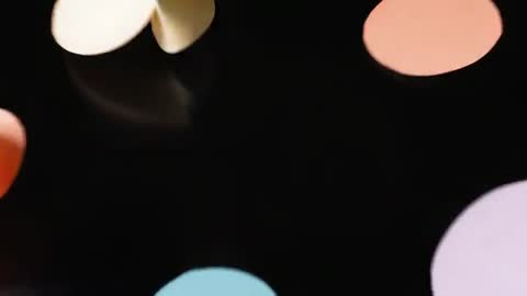 Colorful Paper Circles Rotating on Black Surface with Stylish Movement