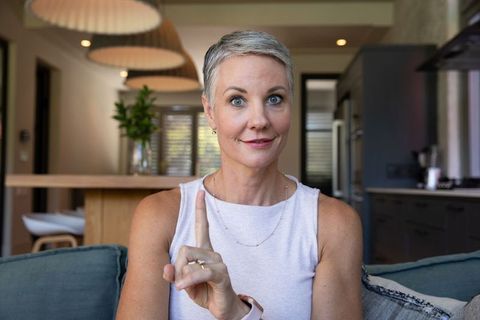 Confident Senior Woman Signaling One in Modern Kitchen Setting