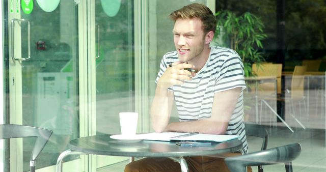 Young Man Sitting at Outdoor Cafe Drinking Coffee - Download Free Stock Images Pikwizard.com