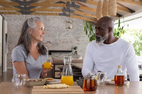 Senior african american man and woman enjoying sunny brunch in modern open-plan kitchen