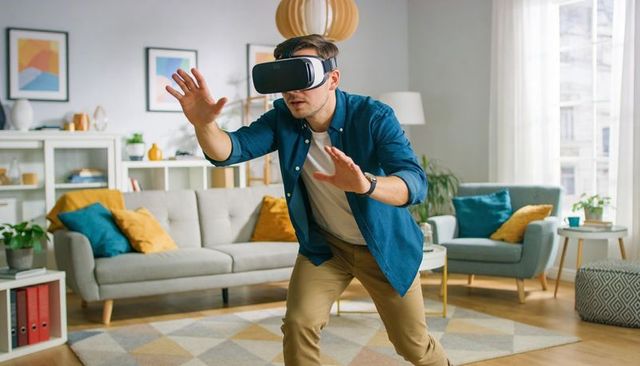 Young man exploring virtual reality at home reaching forward wearing vr headset