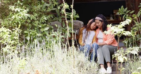 Mother and Daughter Embrace on Rustic Porch Amidst Lush Greenery