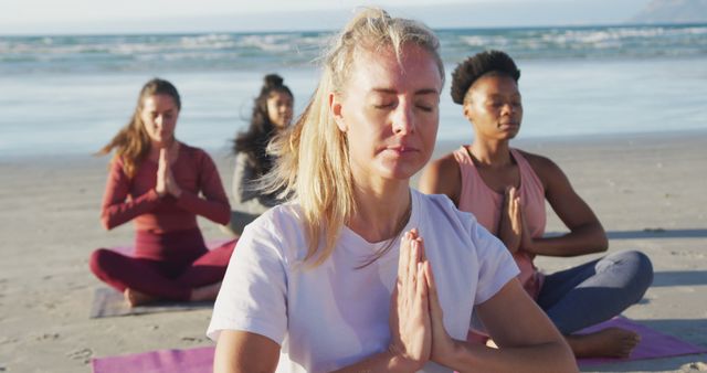 Group of diverse female friends meditating at the beach. healthy active lifestyle, outdoor fitness and wellbeing.
