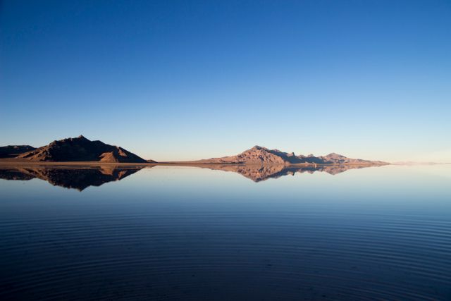 Perfect for use in promotional content for travel and tourism, this image showcases the tranquil beauty of a serene mountain reflection on a calm lake at sunrise. Ideal as a background for nature blogs, meditation apps, environmental campaigns, and outdoor adventure magazines. Emphasizing serenity and natural beauty, it can inspire a sense of calm and wonder in the viewer.