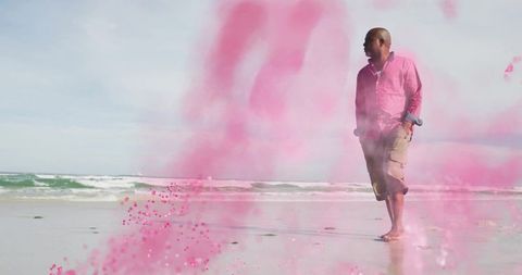 Man walking on beach with pink powder cloud