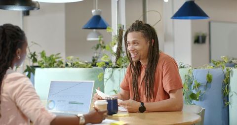 African American coworkers collaborating over laptop and papers in modern coworking space