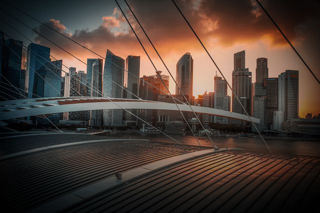 This image captures a stunning sunset over a modern city skyline, highlighting the contrast between innovative architectural designs and a vibrant evening sky. Perfect for use in digital media, marketing campaigns, or travel brochures emphasizing urban landscapes and modern metropolitans.