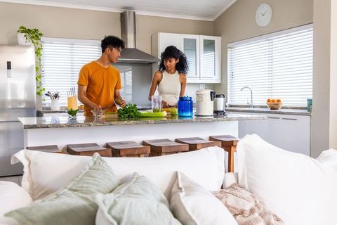 Asian man and african american woman preparing drinks and chopping herbs in modern kitchen