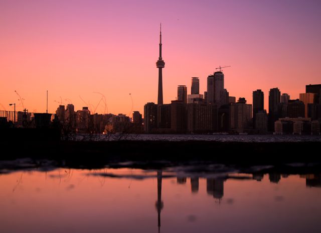 This image captures the stunning Toronto skyline during sunset, with the CN Tower prominently visible. The reflection in the water adds an artistic touch to the cityscape, creating a tranquil and picturesque scene. Ideal for use in travel promotions, urban photography collections, and scenic city landscape projects.
