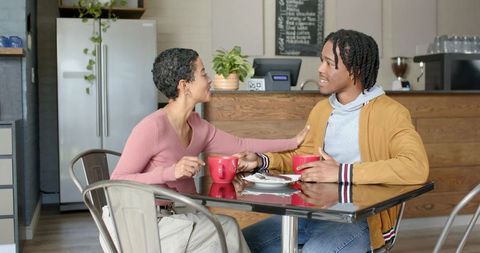 Young couple sharing coffee and conversation in cozy urban café with rustic counter ambience