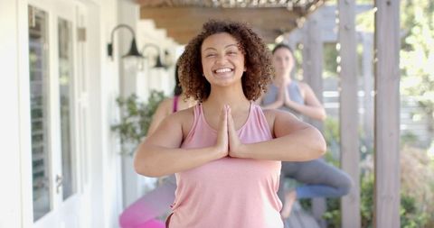 Friends Practicing Yoga Tree Pose on Patio for Wellness and Relaxation