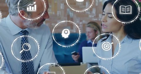 Colleagues discussing analytics on tablet with digital icons for team collaboration