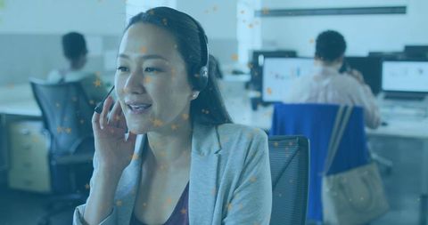 Woman customer service agent wearing headset speaking on call in modern open-plan office