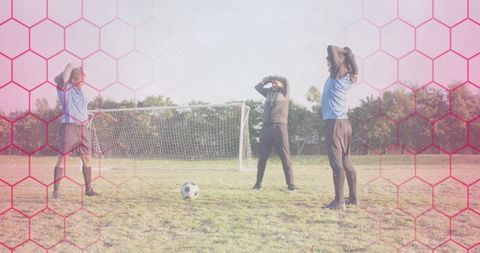 Soccer players reacting to missed shot with goalkeeper and pink hex overlay on grass field