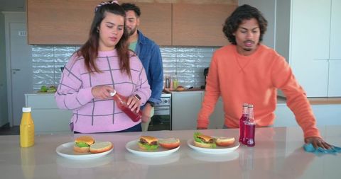 Diverse friends preparing burgers at kitchen island enjoying casual home cooking