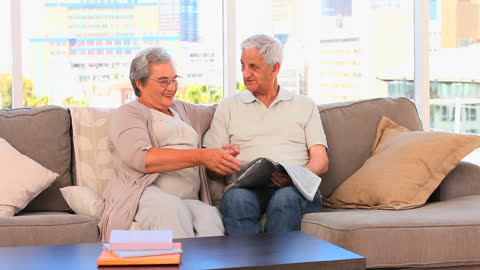Senior Couple Reading Together on Comfortable Couch at Home