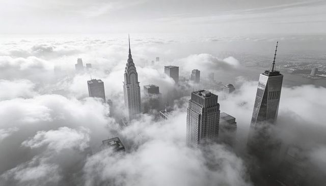 Monochrome aerial of manhattan skyscrapers piercing low clouds with art deco spire