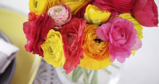 Ranunculus flowers in vibrant red, yellow, and pink create a striking floral arrangement. Perfect for use in marketing materials during spring and summer, as well as for wedding and event planning promotions.
