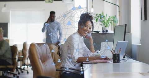 Smiling woman working on laptop wearing headset, collaborating with digital network overlay