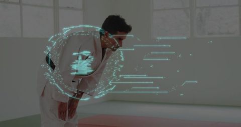 Bowing black-belt martial artist in white gi with cyan digital halo in dojo