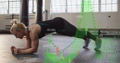 Female athlete holding forearm plank in industrial gym with digital fitness data overlay