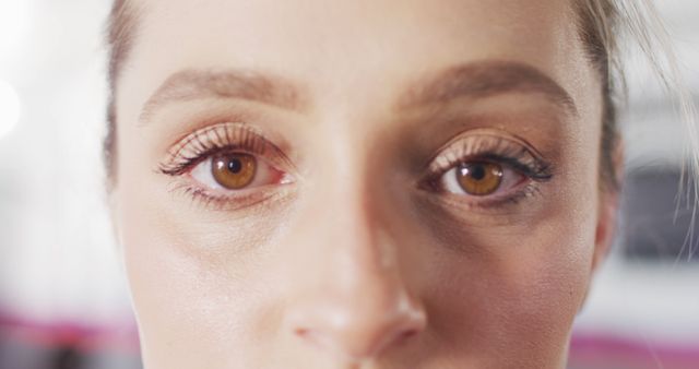 Close-up image capturing a woman with beautiful brown eyes, highlighting her eyelashes, eyebrows, and skin texture. Suitable for beauty and cosmetics advertisements, makeup tutorials, dermatological studies, and eye care promotions.