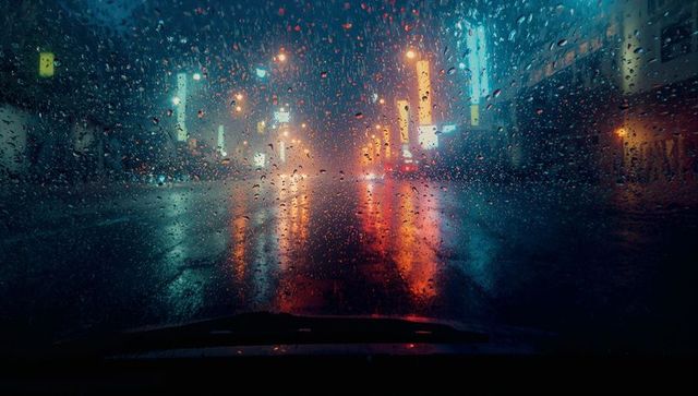 Raindrops on Windshield Refracting Urban Neon Lights