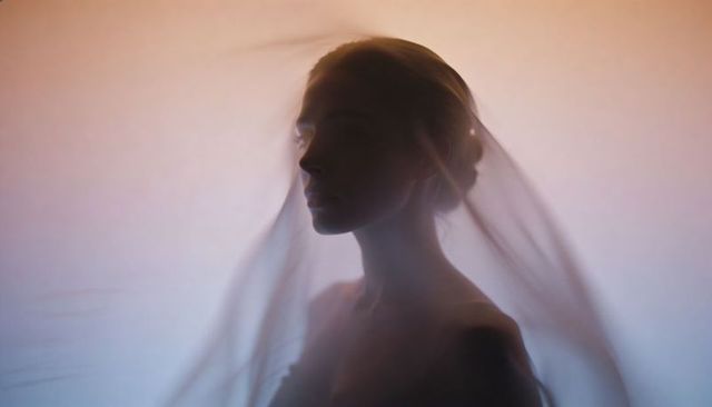 Ethereal veiled silhouette floating in soft backlit gradient minimalist bridal portrait