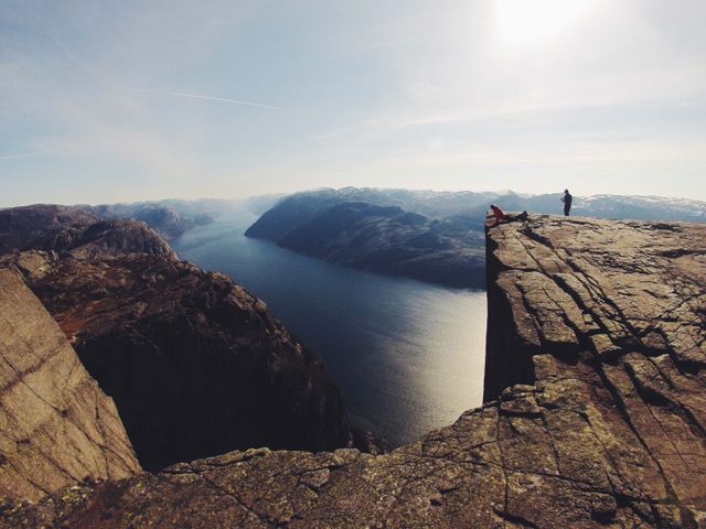 This photo captures a breathtaking panoramic view of Preikestolen, a famous cliff in Norway, overlooking a vast fjord. Ideal for travel brochures, adventure tourism campaigns, and outdoor activity blogs, emphasizing the stunning natural beauty and allure of hiking to scenic destinations.