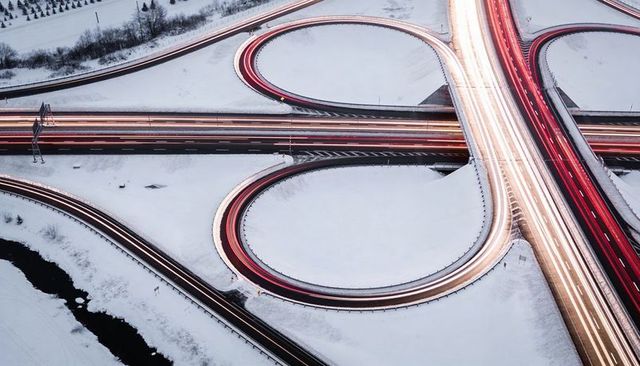 Aerial long exposure cloverleaf highway interchange with light trails on snowy night