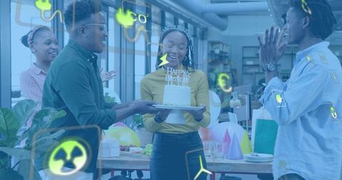Team celebrating office birthday — woman holding cake, colleagues cheering with balloons
