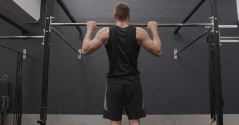 Athletic man performing chin ups at gym for strength training