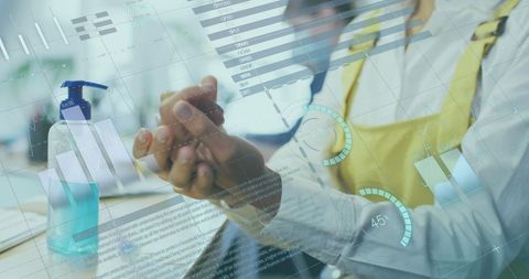 Businesswoman sanitizing hands with financial data interface overlay