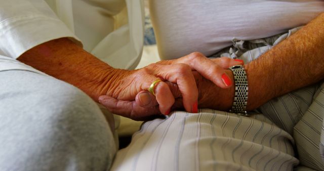 Close-up of senior couple holding hands in bedroom at comfortable home. Mid section of senior couple relaxing on bed 4k