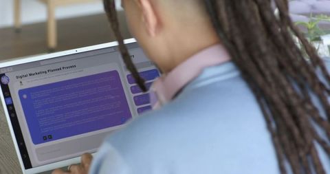 Mid-adult man with dreadlocks working on laptop digital marketing dashboard at home desk