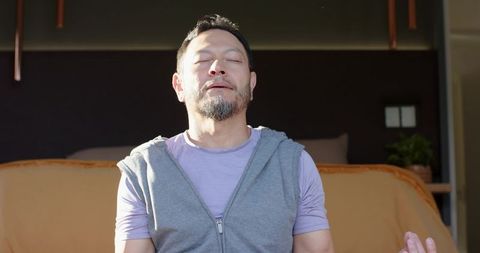 Mature man in meditation pose finding inner peace at home